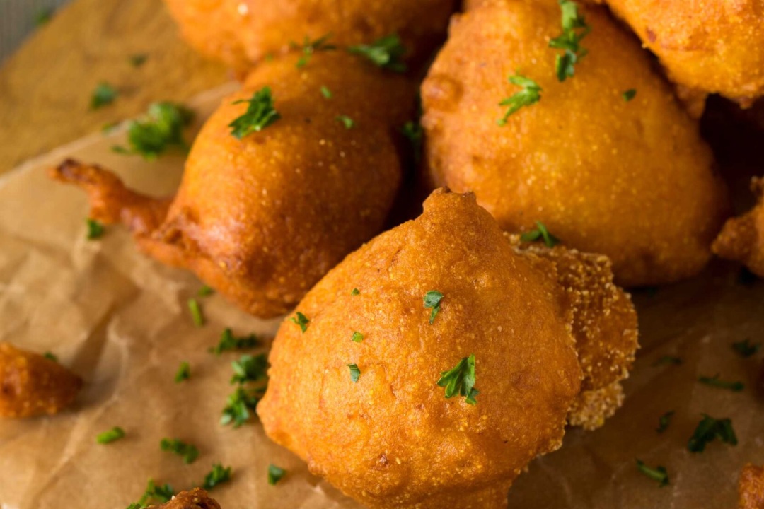 A delectable plate of Hush Puppies, deep-fried to perfection, accompanied by a savory dipping sauce.